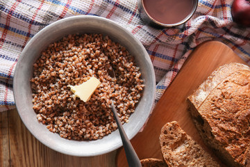 Bowl with tasty boiled buckwheat on wooden table