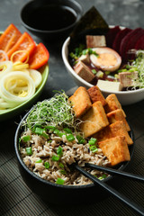 Tasty dishes with tofu cheese in bowls on grey table