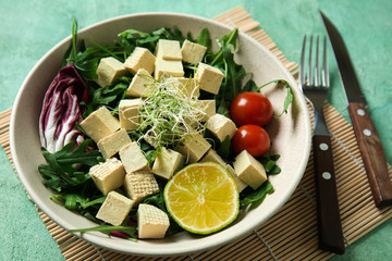 Tasty salad with tofu cheese in bowl on table