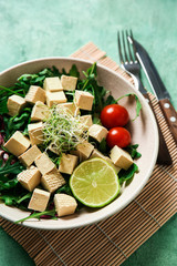 Tasty salad with tofu cheese in bowl on table