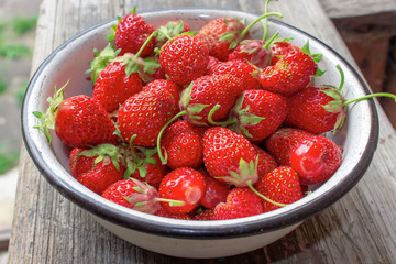 Fresh strawberry in a white plate on wooden table , top view