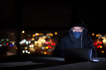 hacker using laptop computer while working in dark office