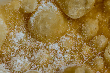 Macrophoto. European dessert angel wings. Interesting tech tour deep fried dough strips with powdered sugar. Site about the kitchen, pastries, sweets.