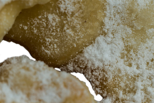 Macrophoto.European dessert angel wings. Interesting texture of deep fried dough strips with with a hole in the middle. Site about  pastries, sweets.