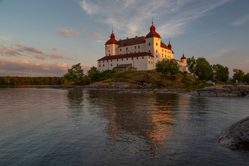 Last sun rays casting a warm light on Lacko castle with reflection in the waters of lake Vanern, Lidköping, Sweden