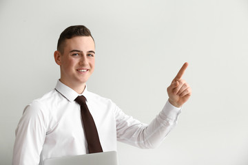 Handsome teenage boy showing something on light background