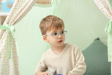 Portrait of cute little boy sitting in hovel at home