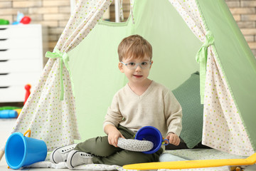 Portrait of cute little boy sitting in hovel at home