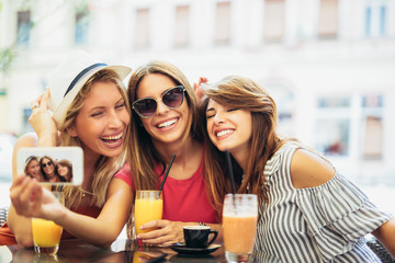 Three young women in a cafe after a shopping make selfie photo