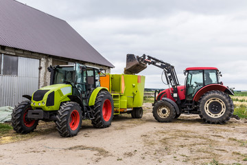 Tractor with front end loader loads the food into a distributor of animal feed for cows. Necessary...