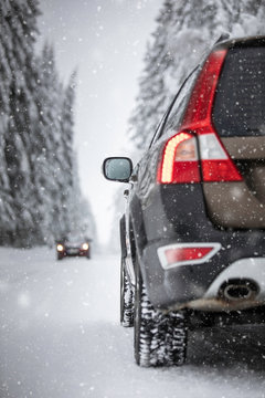 Car On A Snowy Winter Road Amid Forests - Using Its Four Wheel Drive Capacities To Get Through The Snow