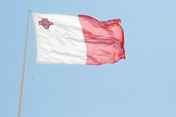 Fototapeta na wymiar National flag of Malta with blue sky on background