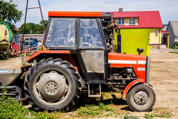 Old tractor for works in a fields , where cultivated corn and grass for the cows . Side view of an agricultural machine . Equipment for a dairy farm.