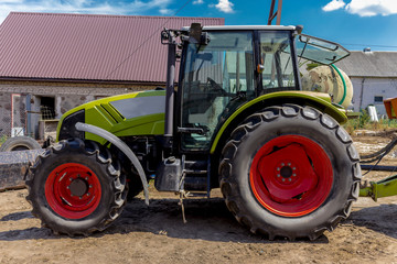 Side view of a powerful tractor for various agricultural works. Necessary equipment for a dairy farm.