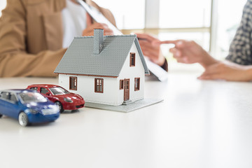 House model with real estate agent and customer discussing for contract to buy house, insurance or...