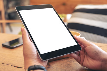 Mockup image of woman's hands holding black tablet pc with blank screen on wooden table in cafe