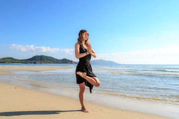 Fototapeta na wymiar yoga on the beach, young girl in black, early morning, fog