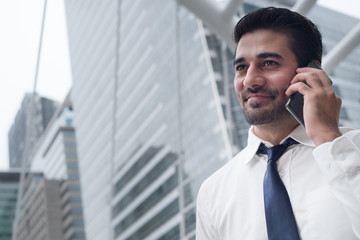 Fototapeta premium happy asian business man talking smart phone; portrait of happy smiling successful Asian, Indian businessman talking via smart phone; negotiation, business deal, transaction, communication concept