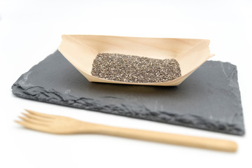 Chia seeds on a wooden bowl on a plate of slate material