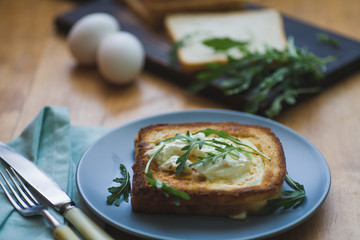 sandwich with egg and arugula on a plate is on the table