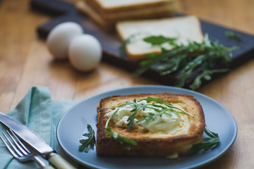 sandwich with egg and arugula on a plate is on the table