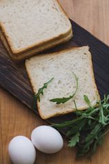 sandwich with egg and arugula on a plate is on the table