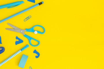 Blue school supplies on a yellow desk.Back to school background