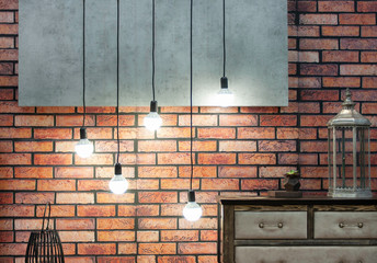Loft-style interior with orange brick wall and lamps on a long wire