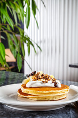 Traditional american dessert for breakfast with copy space. Close up view on sweet stack pancake with pear, cream, nuts. Restaurant food menu, recipe photo
