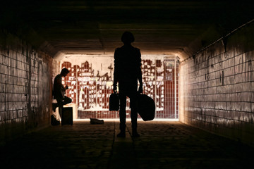 Two street musicians in the underpass. Silhouette photo. Vagrant lifestyle. Playing to make money a...