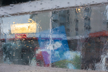Rain drops on car glass, focus on raindrops. View to the street. Parking disc is reflecting in window.