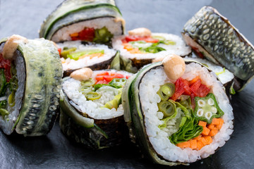 Sushi roll with vegetables on black background. Vegetarian dish.