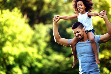 Portrait of young father carrying his daughter on his back