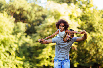 Portrait of young father carrying his daughter on his back