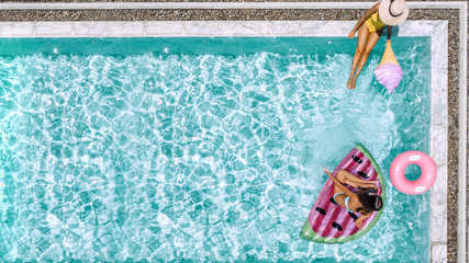 Family relaxing on inflatable lilo in hotel pool - obrazy, fototapety, plakaty