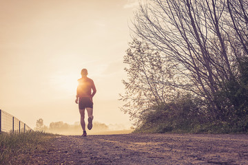 Uomo che corre su strada di campagna all'alba