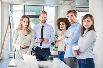 Small group of business people standing and posing at office. Start up business concept. Multi...