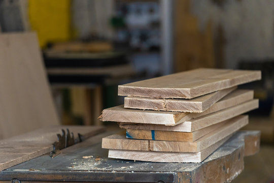 Hobby Wood Concept. Close Up Photo Of Wooden Plank Board On Saw Table In Empty Garage Or Workroom Interior With Blurred Background Focus On Wood