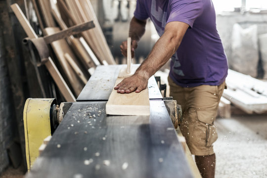 High Quality Wood Small Business Concept. Cropped Photo Of Cabinetmaker Or Handyman Moves Wood On A Woodworking Machine Make Furniture In Garage Or Workroom