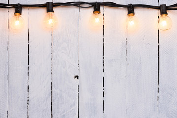 Festive garland glass lamps on wooden white painted wall with copy-space
