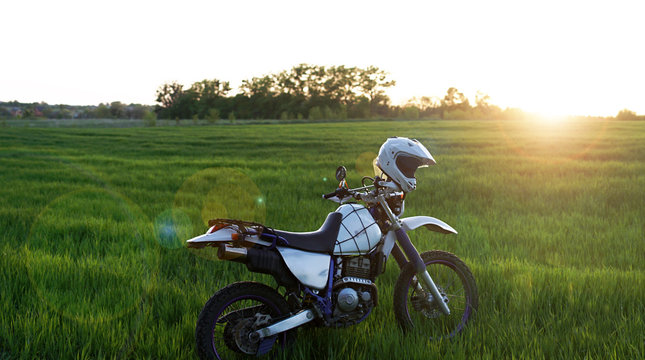 enduro off road Motorcycle on green grass hill landscape pine forest sunset