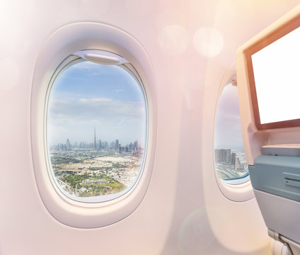 Airplane interior with window view of Dubai city, UAE. Concept of travel and air transportation.