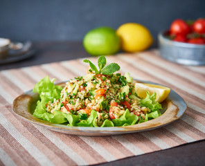 Tabbouleh salad with quinoa. Eastern food with vegetables mix, vegan diet. Side view, linen napkin, old plate