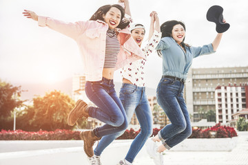 Millennial asian women jumping outdoor - Focus on center female face