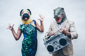 Crazy senior couple dancing for party wearing t-rex and chicken mask - Old trendy people having fun...
