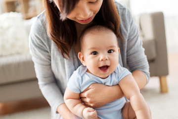 family and motherhood concept - close up of happy young asian mother with little baby at home