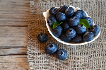 Freshly picked organic blueberries in a white bowl on a burlap cloth background. Blueberry. Bilberries.Healthy eating,vegan food or diet concept.Selective focus.