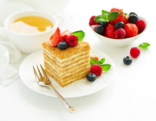 A piece of multi-layered honey cake with fresh berries. Selective focus