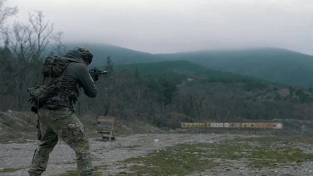 A group of military men in camouflage uniforms are conducting tactical shooting from military weapons on a training dash at targets.