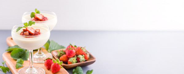 Delicous and nutritious double color (colour) strawberry desserts with mint and diced sarcocarp topping isolated with airy blue background, copy space, close up